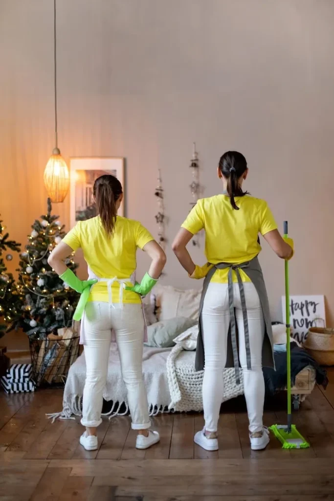 Two professional cleaners in uniform standing ready to perform a deep cleaning service in an East London home