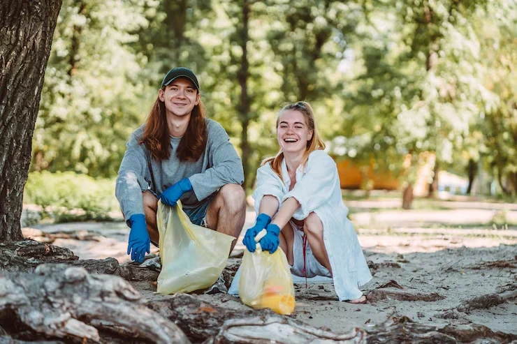 Two young people wearing rubber gloves collecting waste outdoors representing Pearl Lemon Cleaners commitment to green cleaning in East London