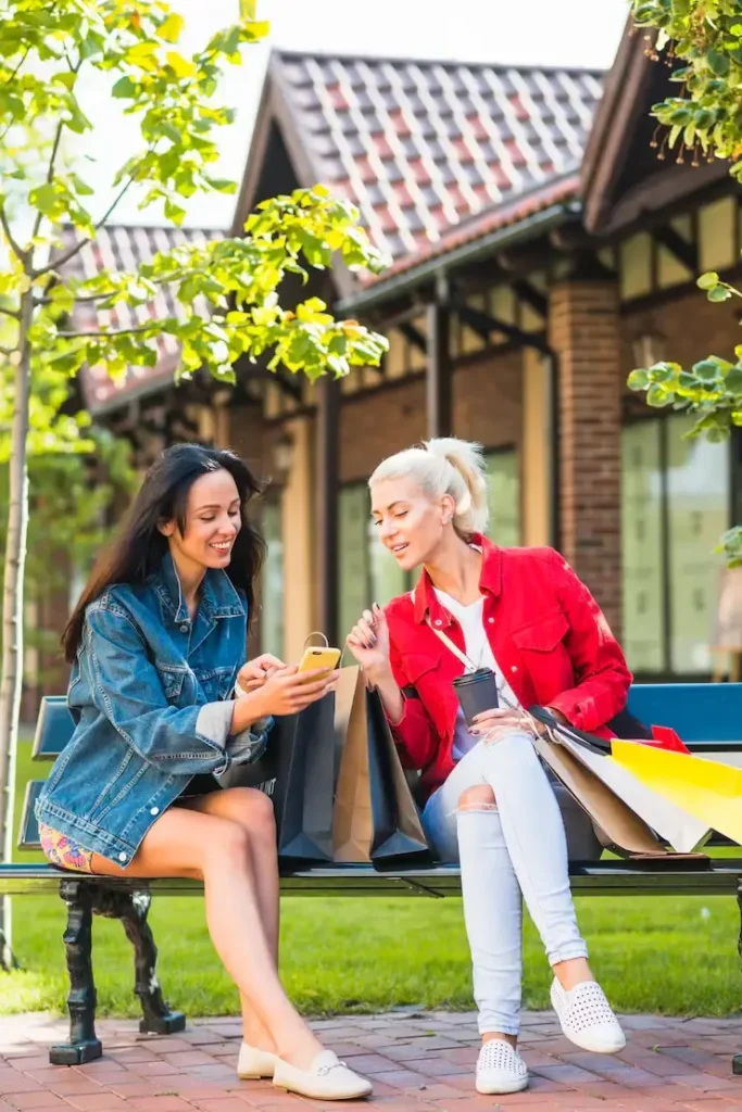 Two East London residents sitting outdoors reviewing a local home cleaning service on their phone after a day out