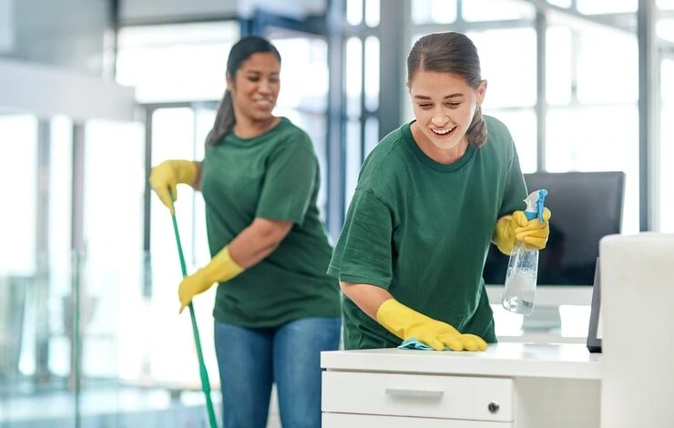 Two professional cleaners in uniform mopping and wiping surfaces during a regular home cleaning visit in East London